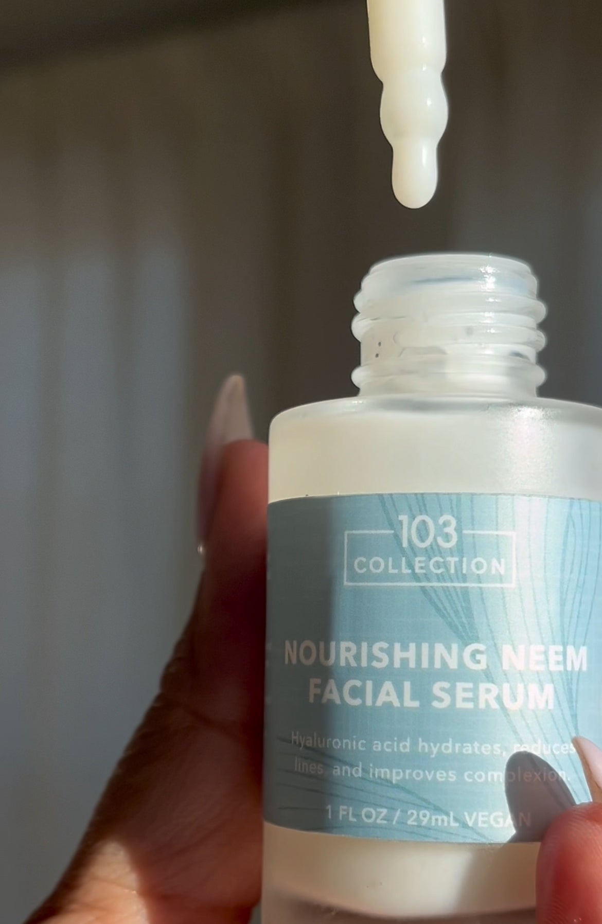 Applying Vegan Nourishing Neem Facial Serum with dropper for hydration and skin protection, featuring hyaluronic acid and niacinamide.