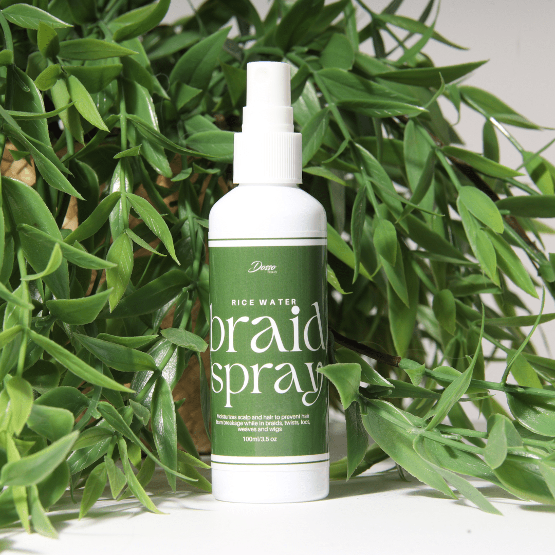 Rice Water Braid Spray bottle with green leaves backdrop, designed to strengthen and moisturize braids, twists, locs.