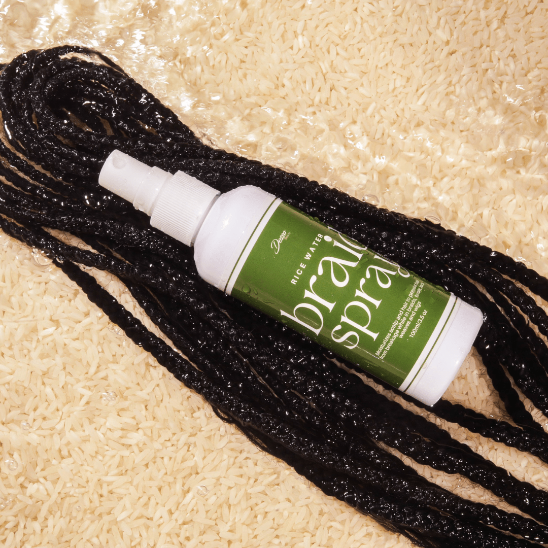 Rice Water Braid Spray bottle on black braids and rice, showcasing hair strengthening and moisturizing for protective styles.