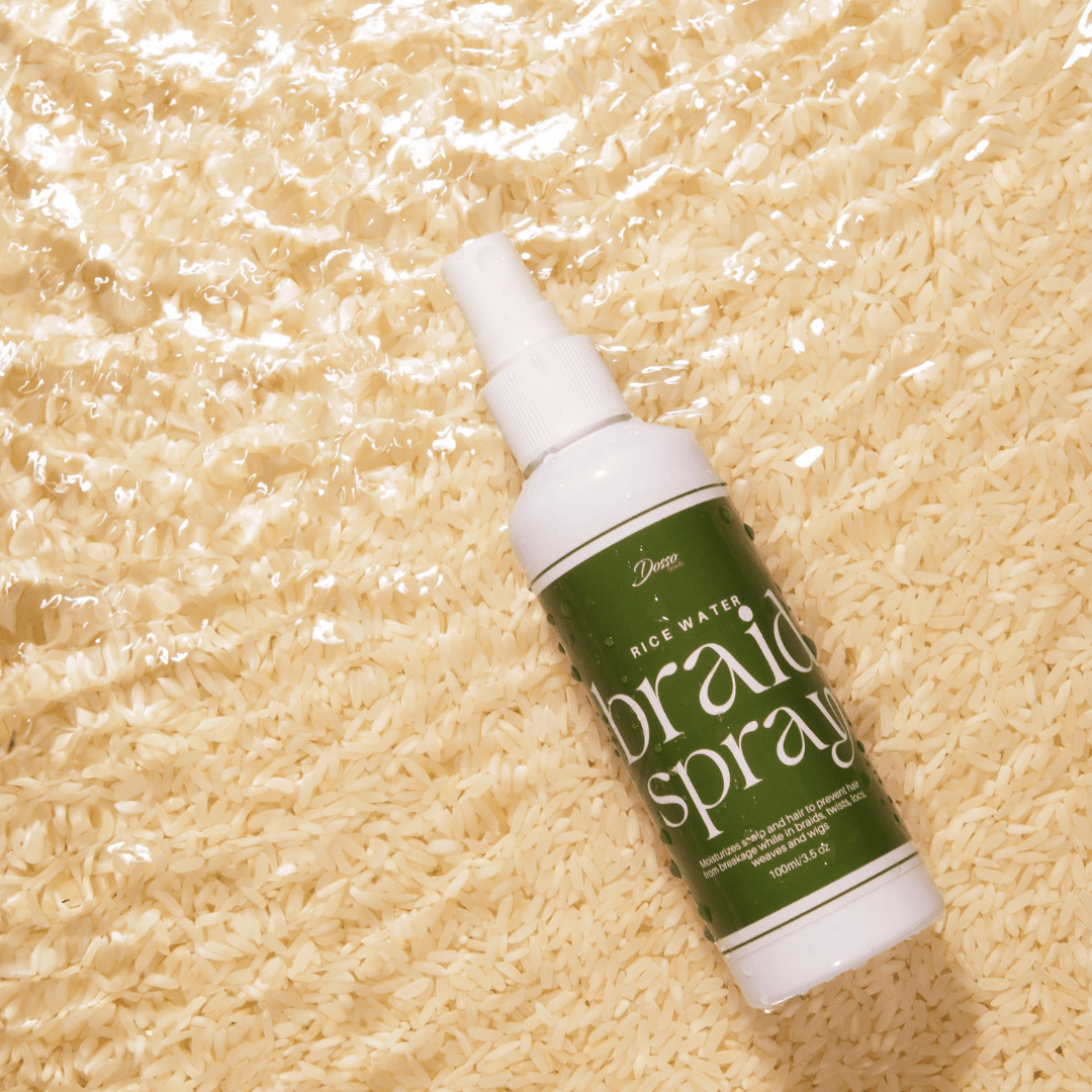 Rice Water Braid Spray bottle on wet rice texture, promoting hair hydration and strength.
