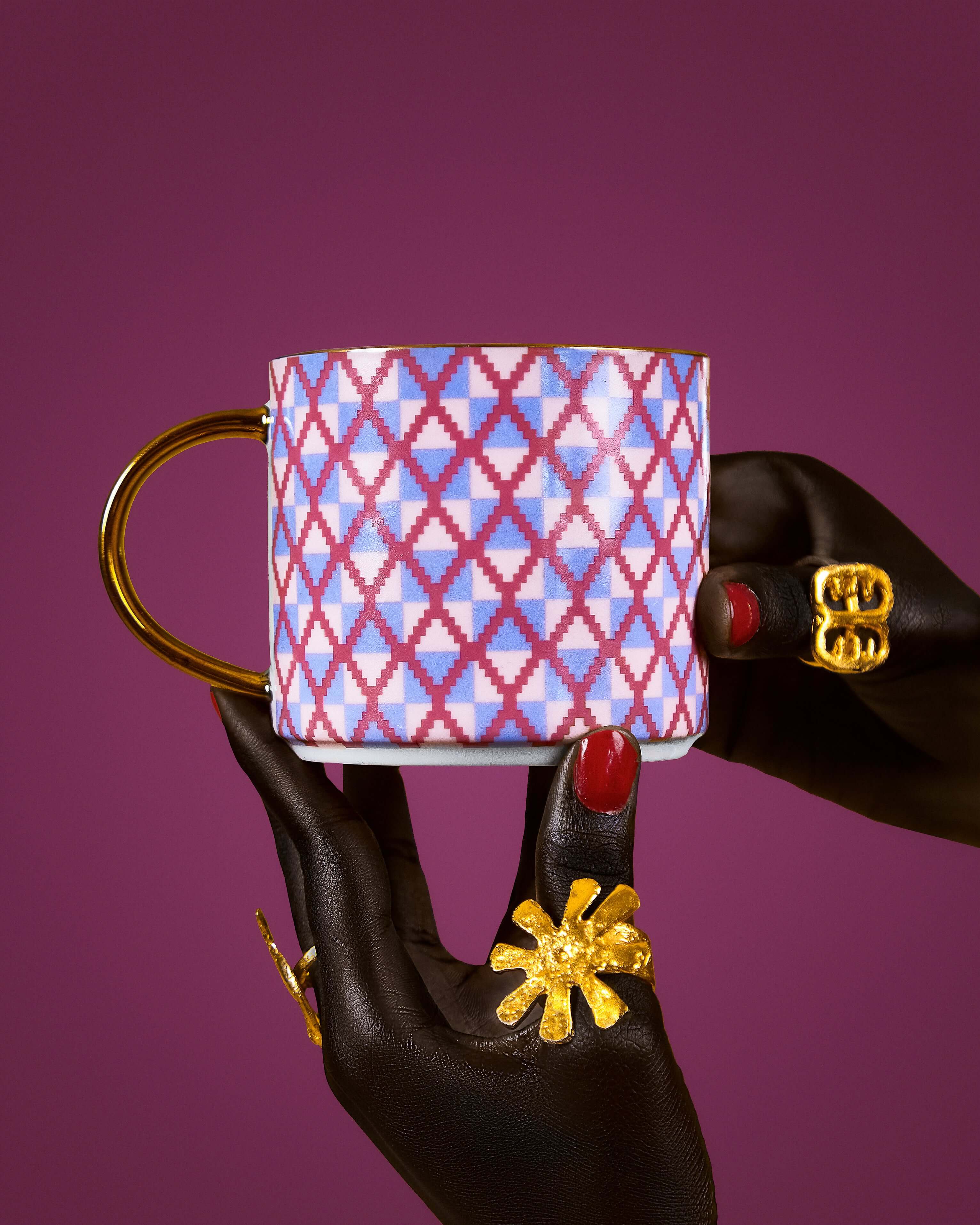Kente-inspired Pink Majesty mug with gold rim held by a hand adorned with golden rings, showcasing femininity and opulence.